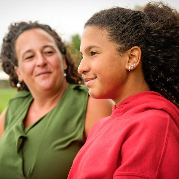 FAMILY COMMUNITY Teen looking away from the camera portrait with her mother in background looking at her