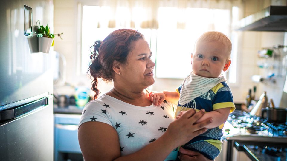 KINSHIP CARE auntie holding her infant nephew with caring look in her eyes who she is looking after for her sister