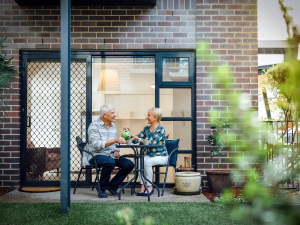 Resident outside her apartment with partner at Westhaven pouring tea